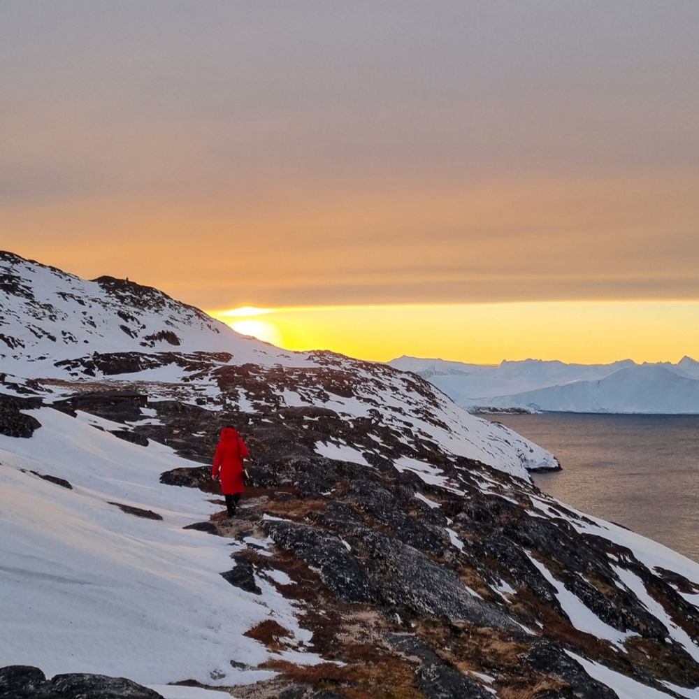 On the way to the icefjord. Walking over brown hills partially covered by ice