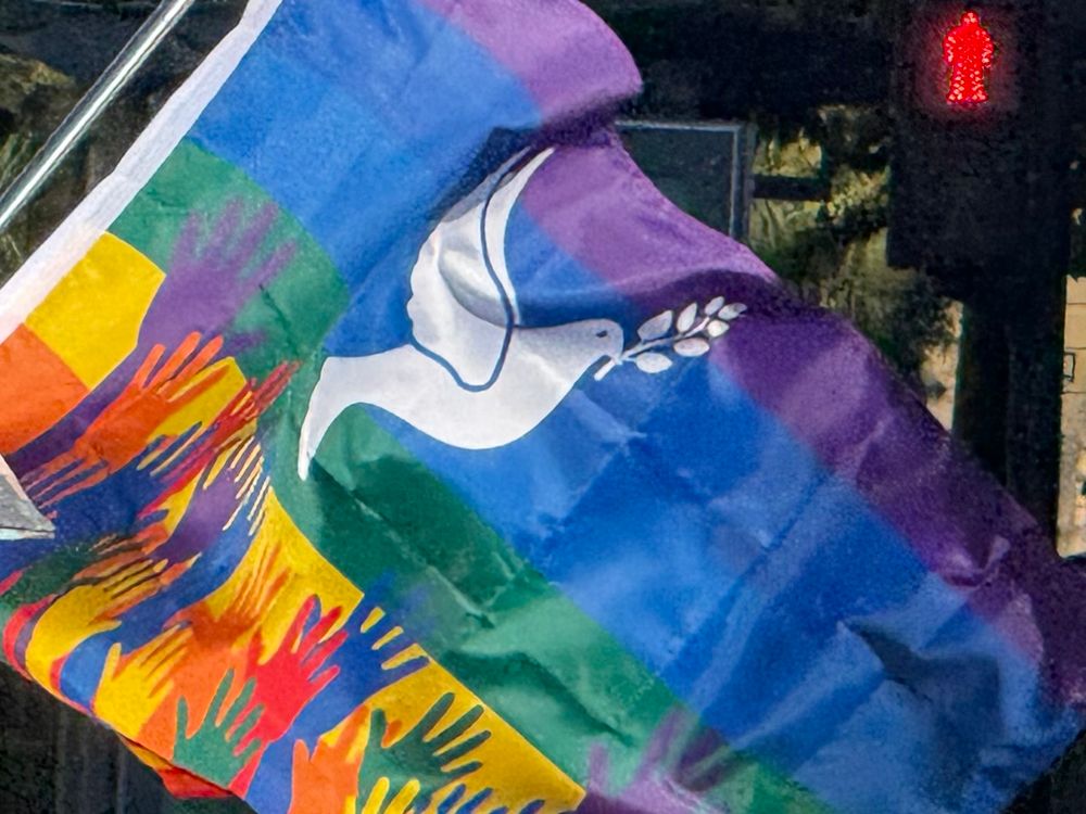 Rainbow flag with a peace dove and a lot of colorful hands