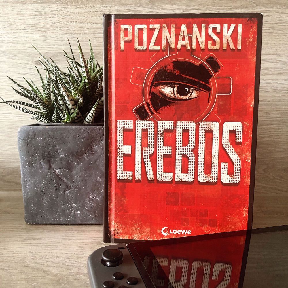 Das Buch steht rechts neben einer Pflanze, davor liegt eine Nintendo Switch.