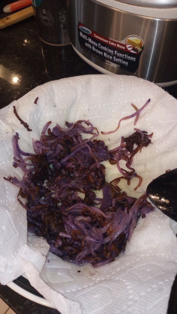 A clump of delicious hashed browns made from purple potatoes sitting on a white paper towel.