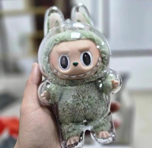 a photo of a labubu inside of a plastic shell, held in somebody's hand