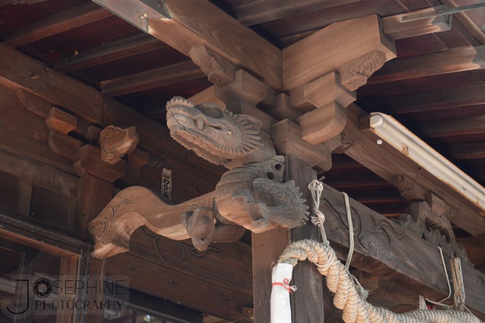 an image of a dragon carved out of wood with a crack through its mouth at the ceiling of the deck of a shrine 