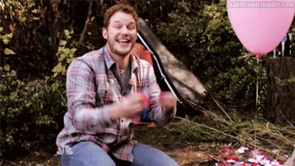 a man in a plaid shirt is holding a pink balloon in front of a tent and flowers