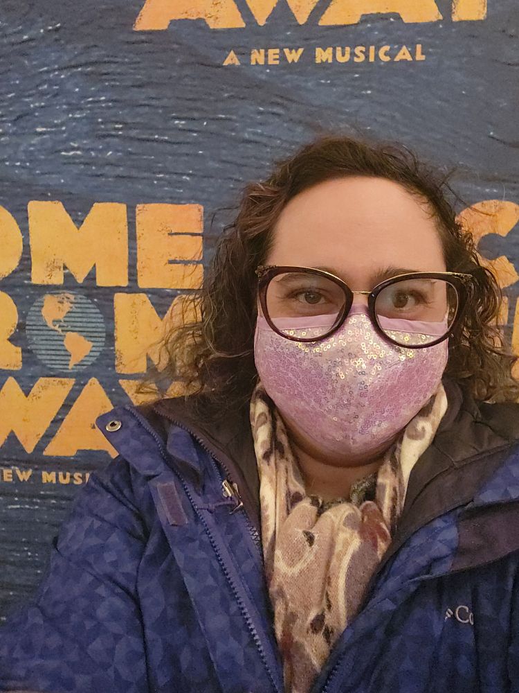 Melinda in front of the Come From Away photo backdrop. 