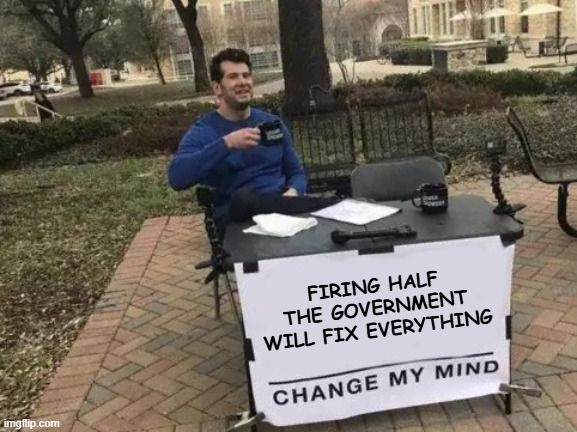 The "Change My Mind" meme featuring a man sitting at a small outdoor table in a park, holding a coffee mug. The table has a sign attached to the front that reads, "Firing Half the Government Will Fix Everything. Change My Mind.