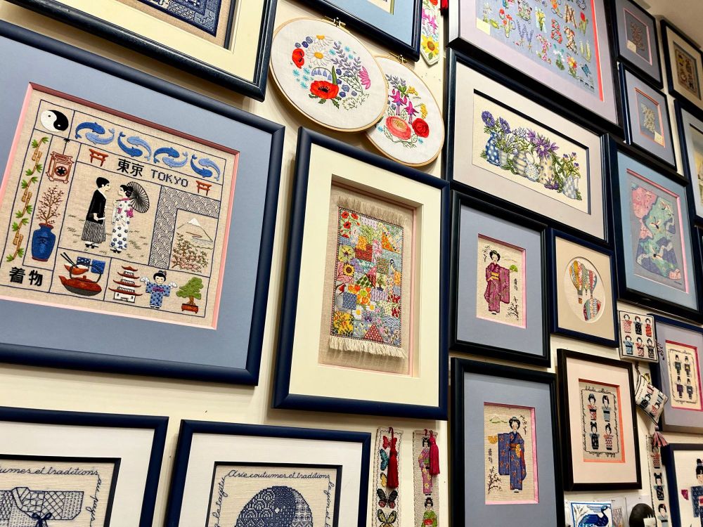 A close-up view of stitched cross stitch designs hanging in Le Bonheur des Dame needlework shop in Paris, France.