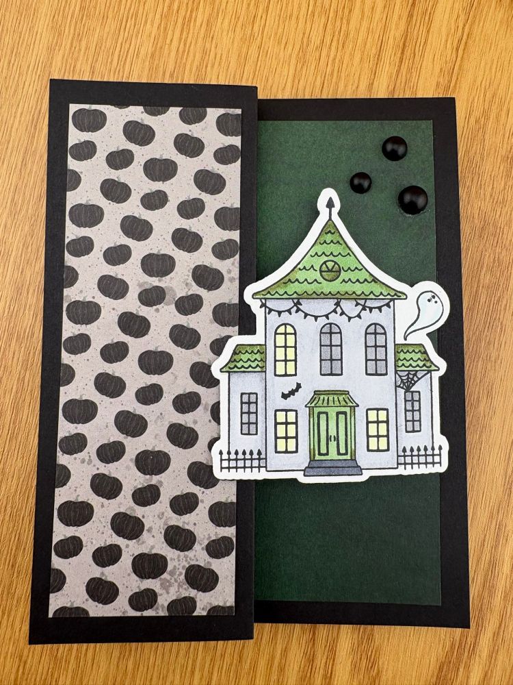 A handmade greeting card featuring a grey and green haunted house on a grey and green background.