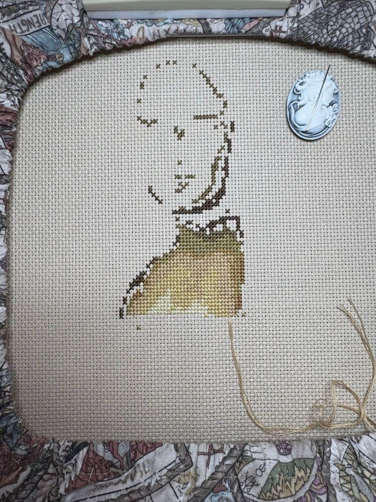 A cross stitch piece of a person in progress.  