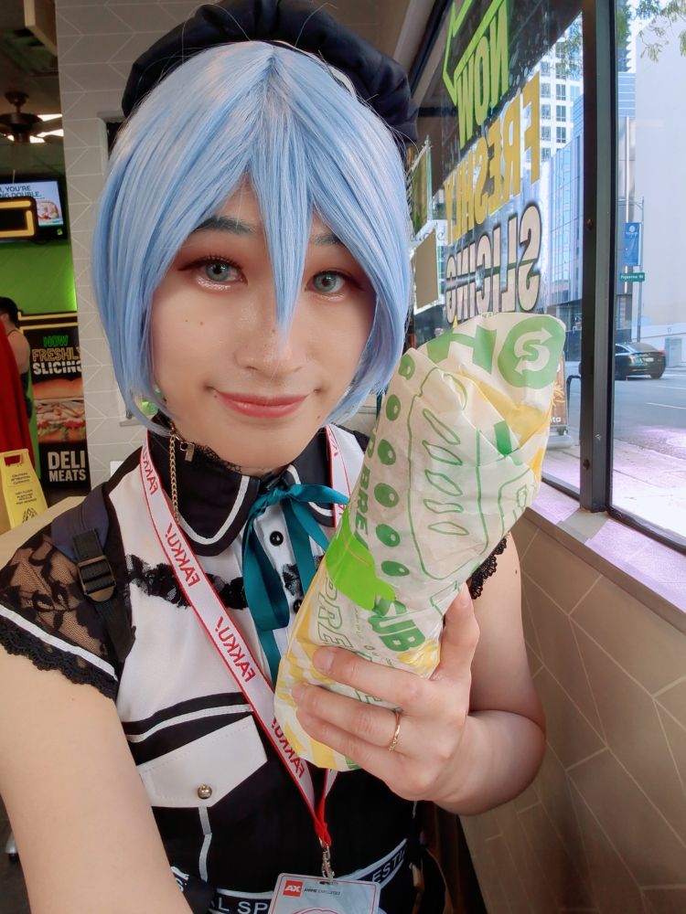 hoshimachi suisei cosplayer holding a Subway footlong