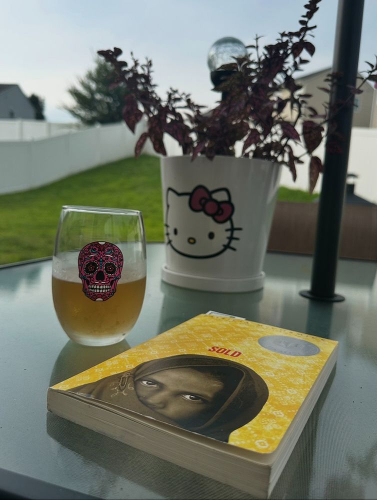 Sold by Patricia McCormick on a patio table with a glass of wine and a potted plant in the background 