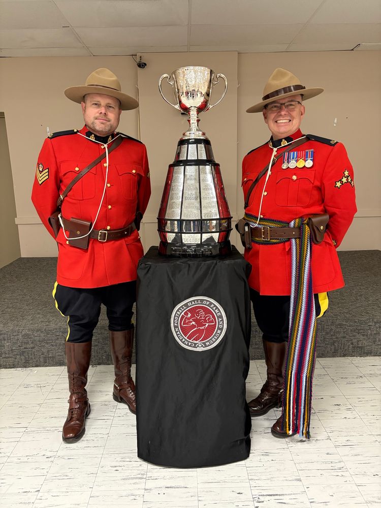 The Grey Cup with smiling uniformed RCMP officers standing on either side 