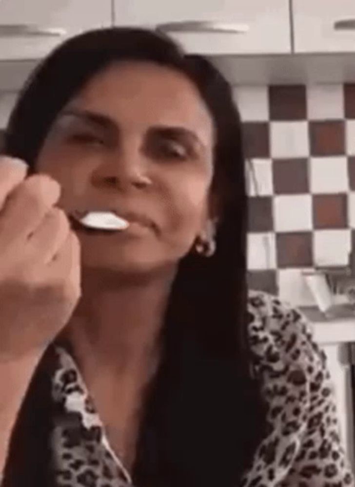 a woman is eating with a spoon in her mouth .