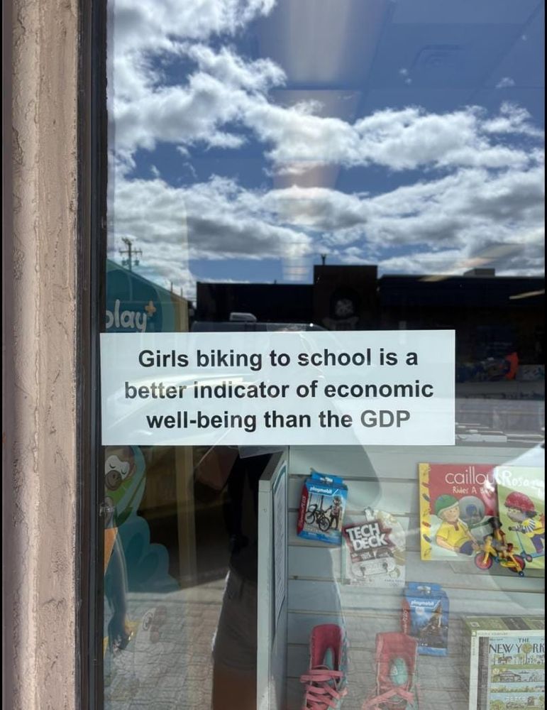 A sign saying "Girls biking to school is a better indicator of economic well being than the GDP"