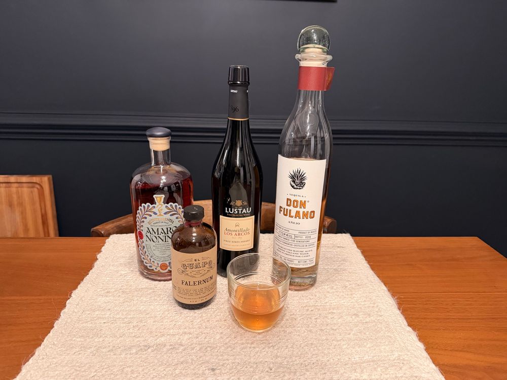Photo of the ingredients used in the cocktail along with a glass of the cocktail