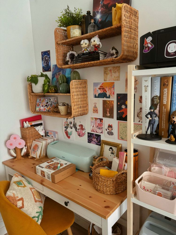Photo of my studio: shelves with books, art supplies, prints, baskets, etc. desk with and baskets, plants, etc. yellow chair with pillow.