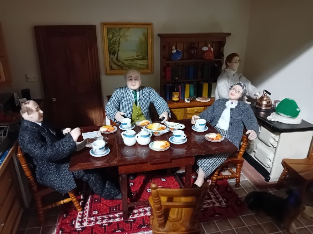 A dollshouse family are having a meal.