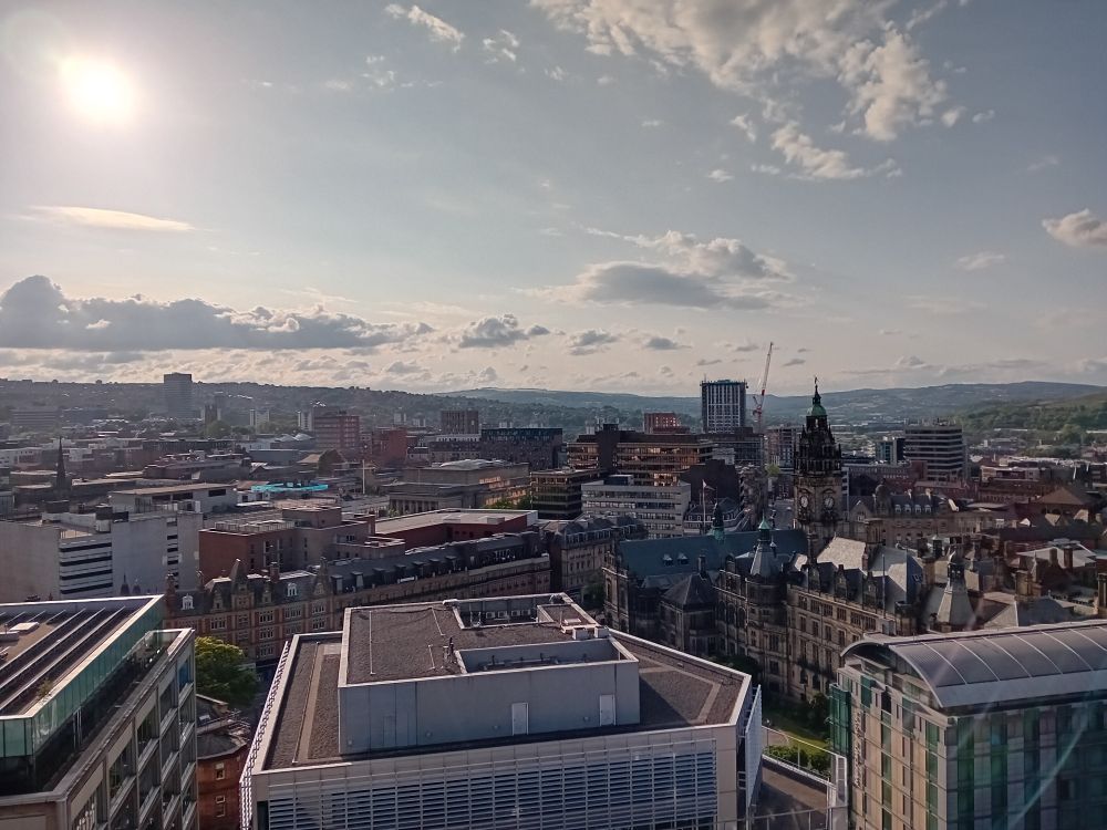 A view of city roofs from the 19th floor, with a summer evening sky