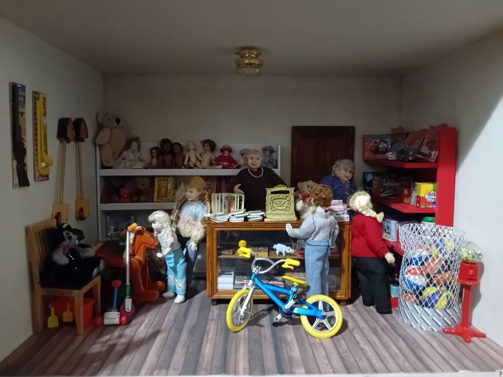 A dolls house room, showing the inside of a toyshop with staff and children