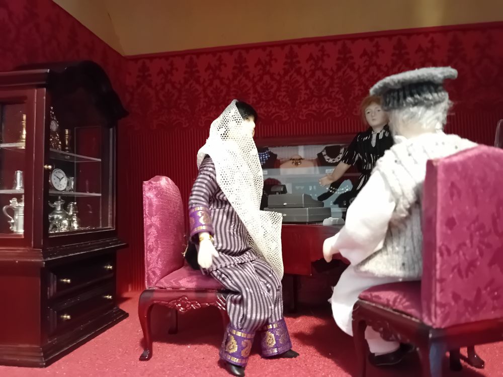A dollshouse scene inside a jewellers, with a mini woman in shalwar 