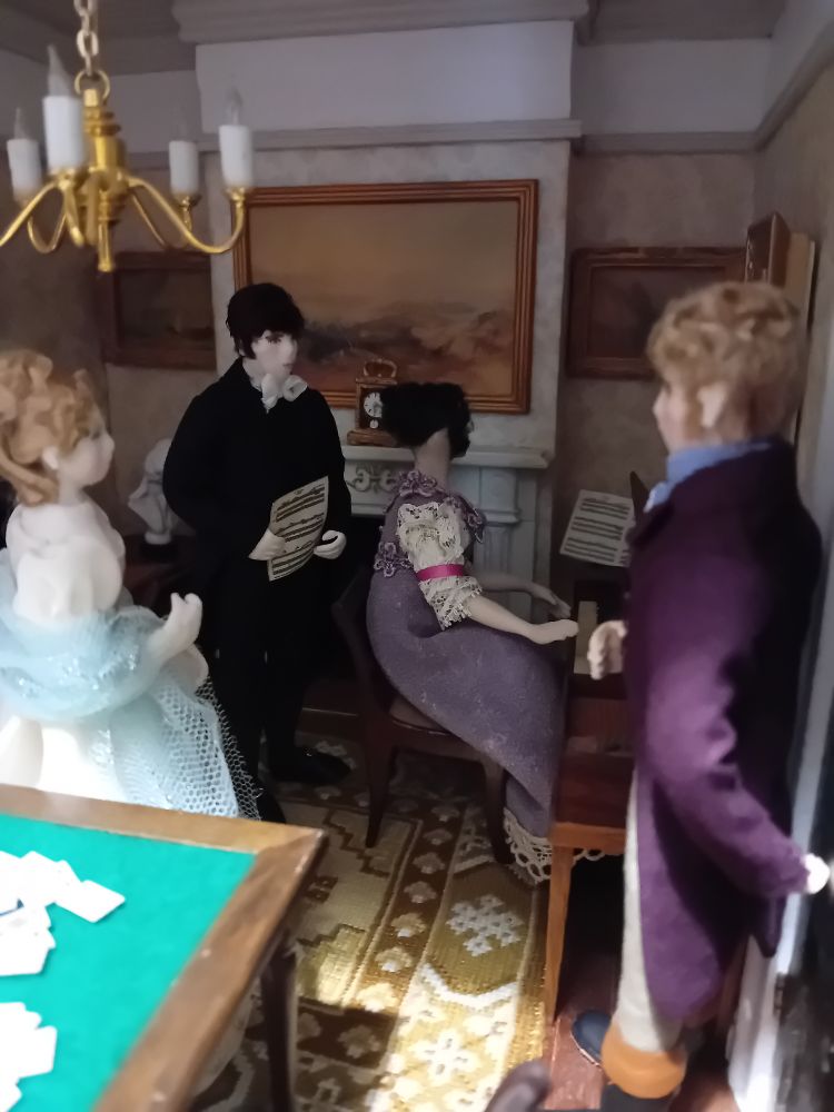 A Regency dollshouse drawing room. A lady plays the piano while another lady and two men stand listening.