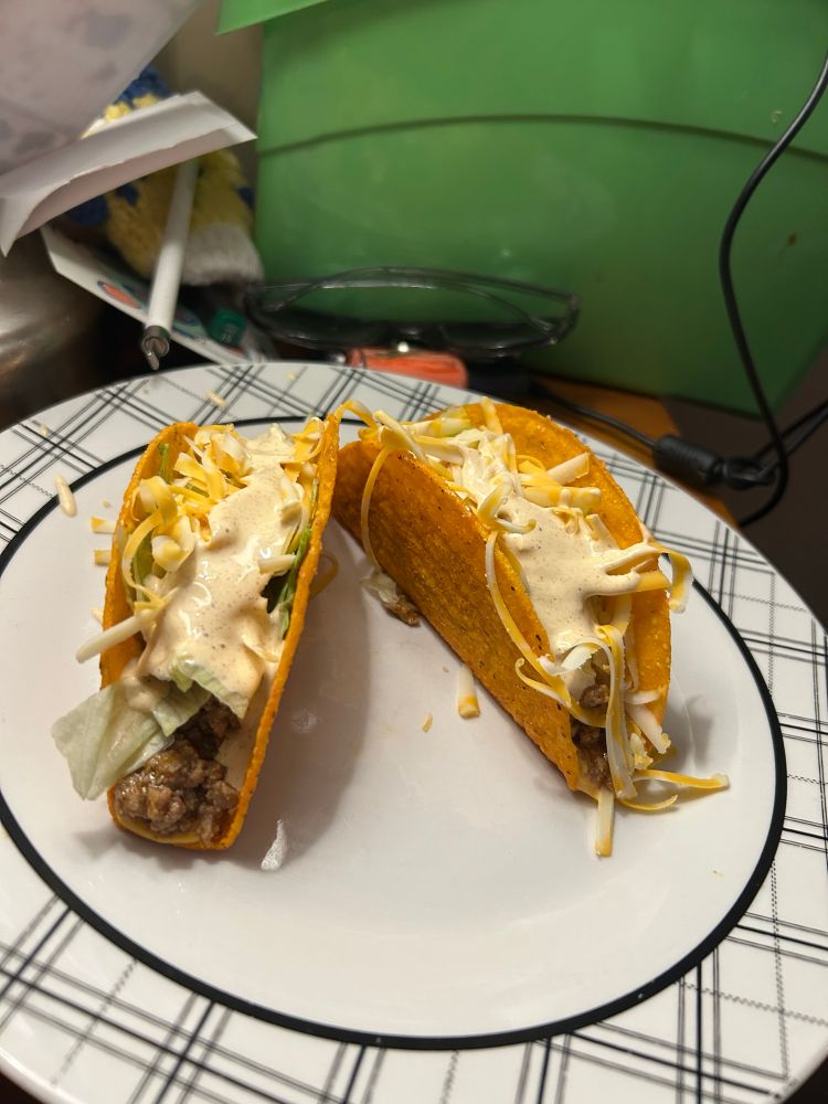 some cheesy taco shells with meat, salsa con queso, lettuce, shredded cheese and a homemade taco sauce sid made 