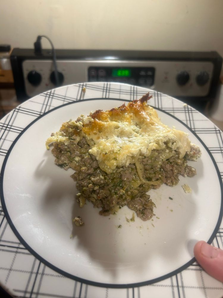 a photo of a plate with sausage and spinach alfredo lasagna sid made 