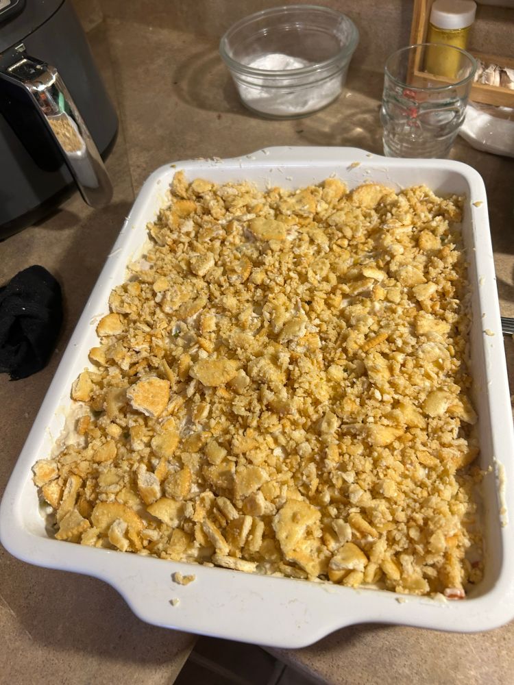 a casserole dish with all the chicken mixture but covered in all the crushed buttered ritz crackers 