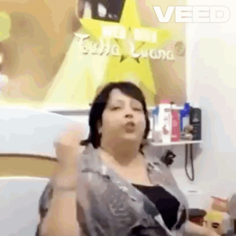 a woman is making a funny face in front of a sign that says veed .