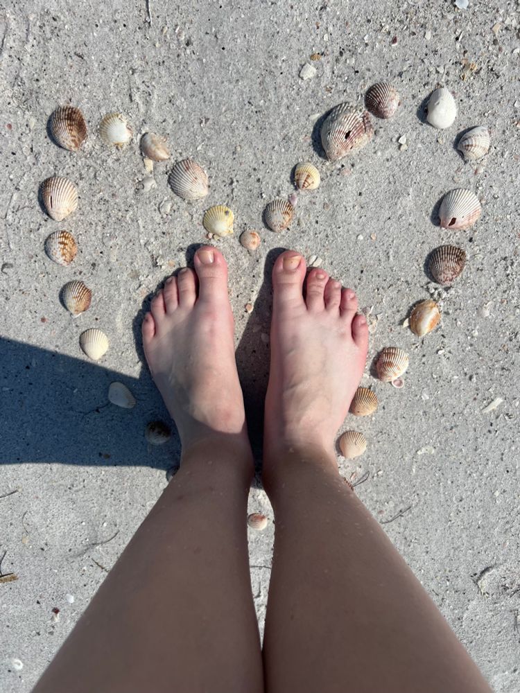 My feet are sinking into the sand, in the middle of shells arranged to look like a heart. 