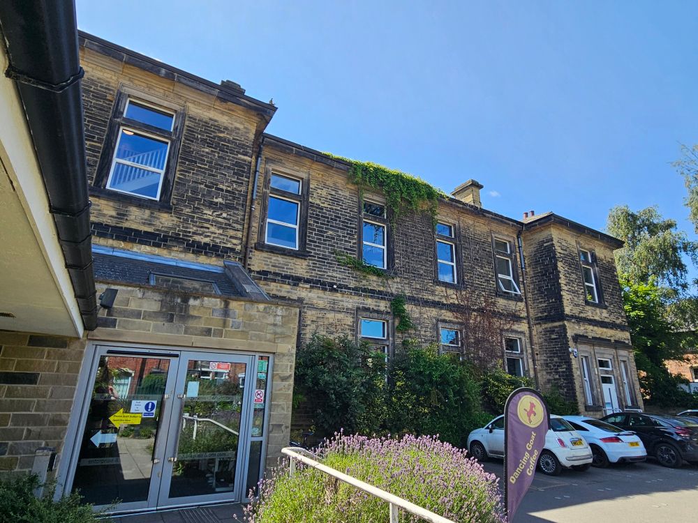 Landscape photo of the Heart Centre, Headingley: lovely old Yorkshire limestone building, with ivy climbing the walls, sagging windows, lavender shrubs at the front, blue sky above 