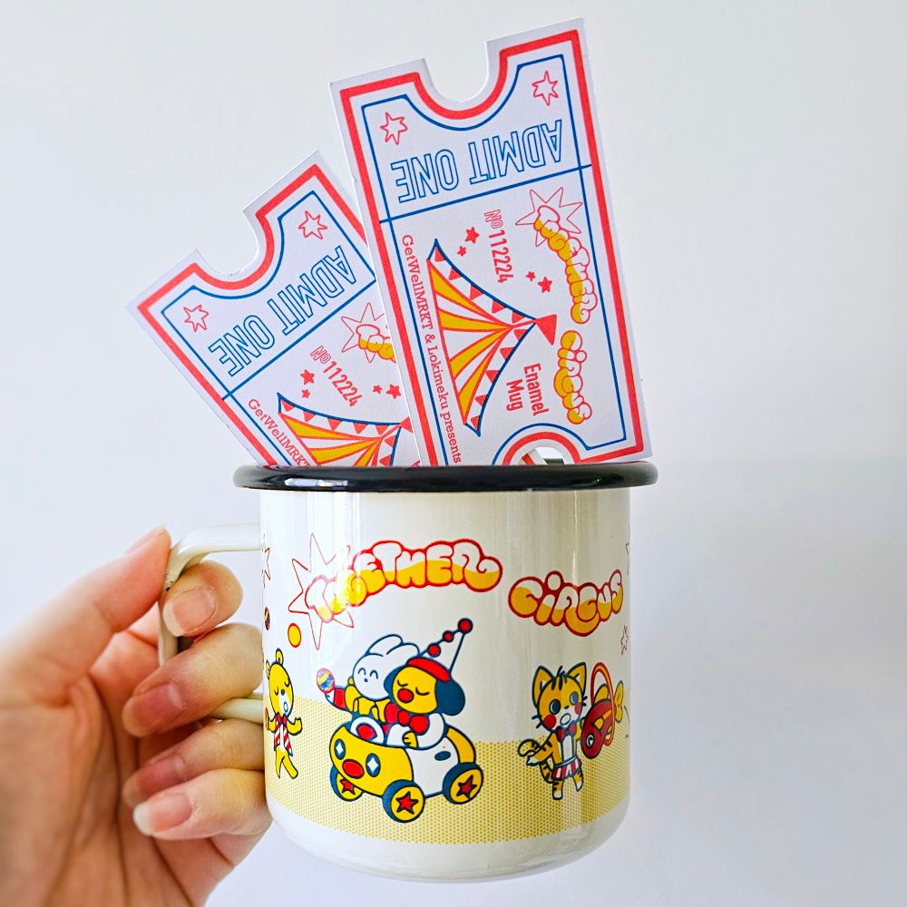 Cream colored enamel mug with cute illustrations of circus characters in red, yellow, and dark teal. The text reads "Together Circus". There are two tickets in the mug that says "Admit One". 