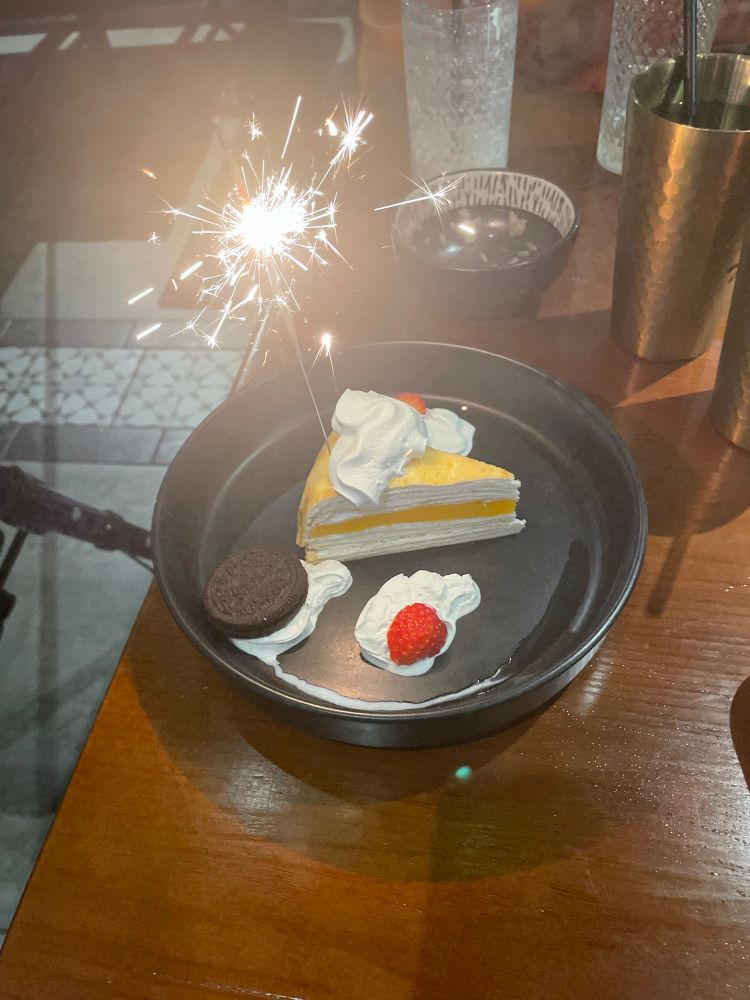 A photo of a crepe cake I received on my birthday. It was mango flavored and had a sparkler attached to it 