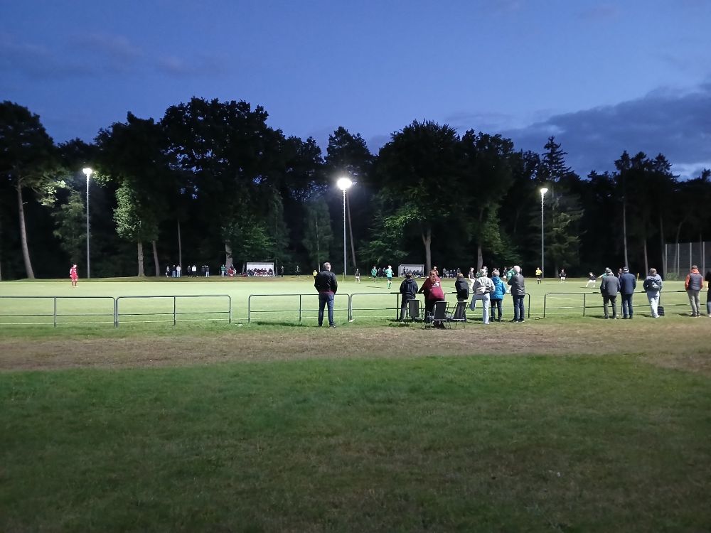 Spielfeld vom Lothar-Heindorf-Platz mit eingeschaltetem Flutlicht in der Dämmerung. 