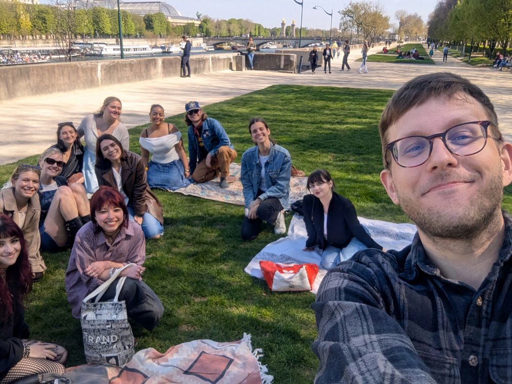 David + students on a grassy patch next to the Seine