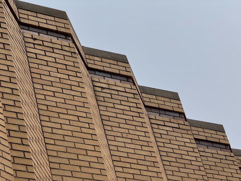 Color photo of the folded facade of tan brick that gives this part of the theatre its distinctive appearance. 