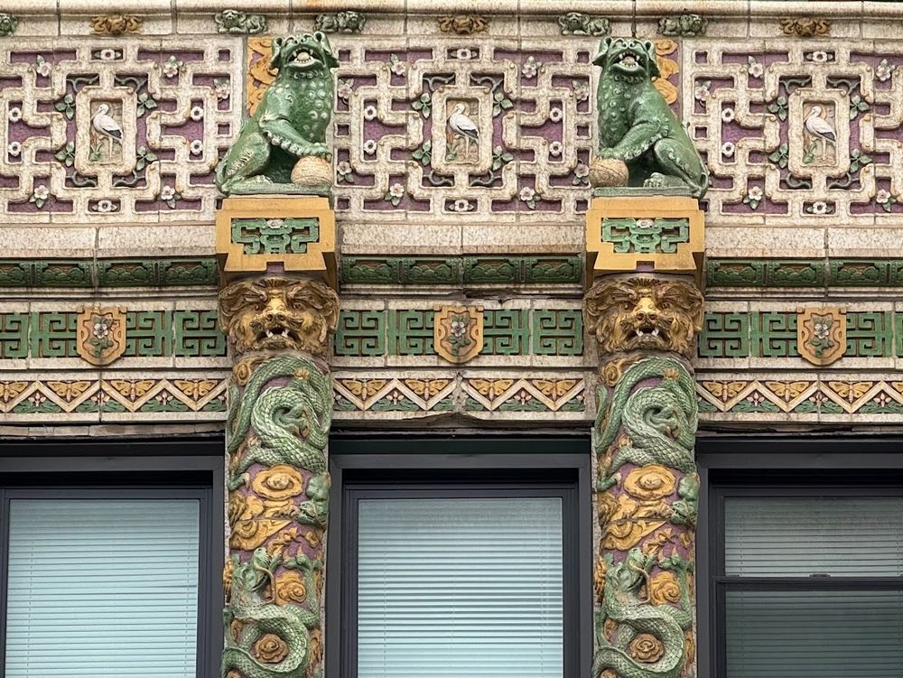 Color close-up of and underneath a balcony. Every inch is encrusted in exquisite polychrome terra cotta. We've got dragons in several sizes and colors, lions, butterflies and birds in the center of a highly detailed symmetrical maze-like pattern, along with gorgeous floral details, all in terra cotta.