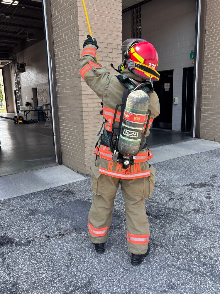 A fire chief in full turnout gear, including a self-contained breathing apparatus (SCBA), actively participating in an air consumption drill. 
