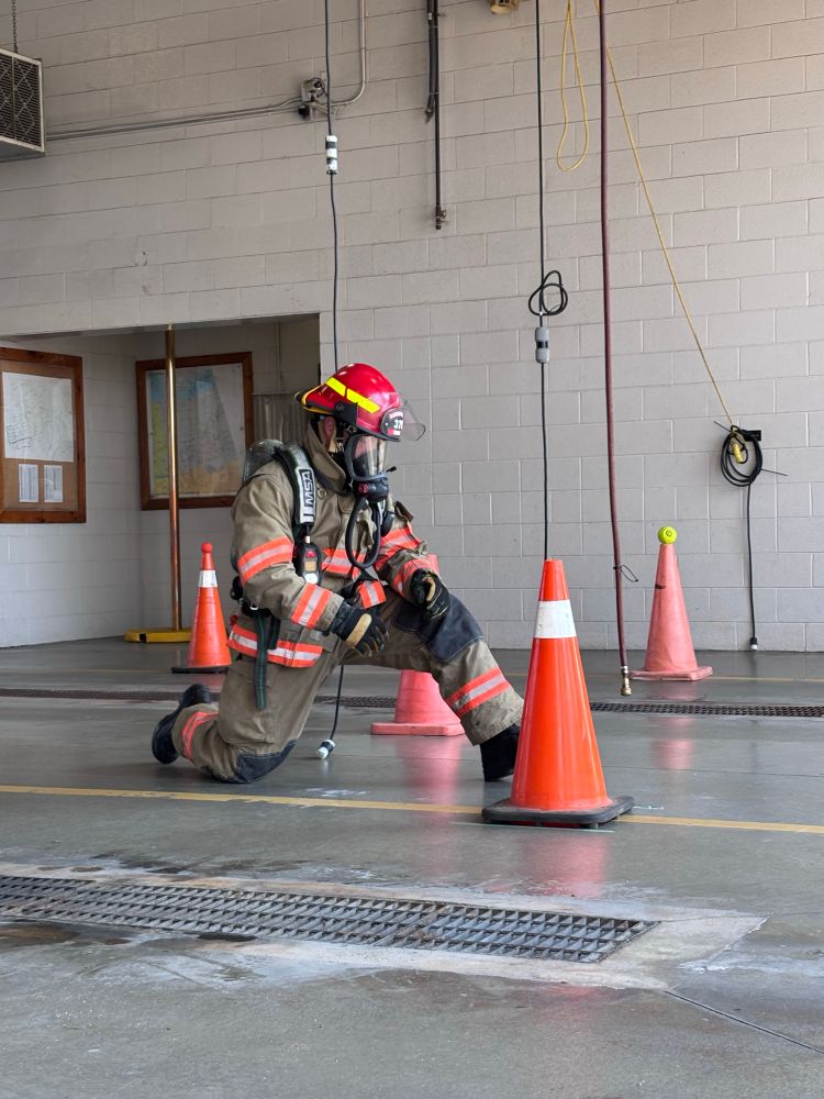 A fire chief in full turnout gear, including a self-contained breathing apparatus (SCBA), actively participating in an air consumption drill. 
