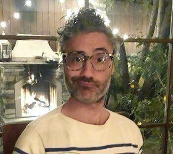 Taika Waititi wearing glasses, short beard, and a smirking expression