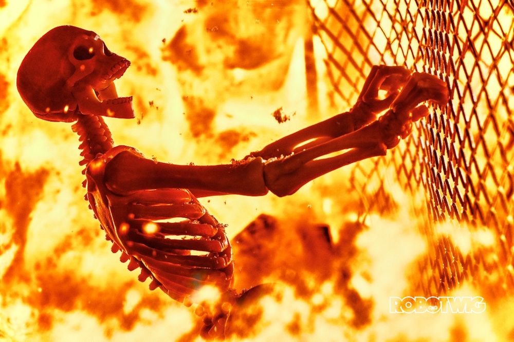 A skeleton holding onto a wire fence fire and explosions all around