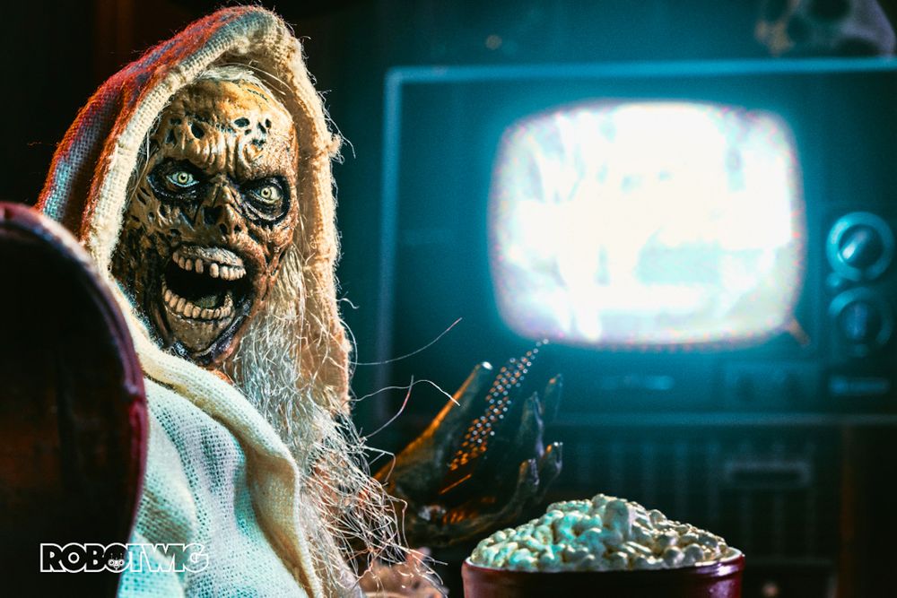 The Creep sits on a chair with Popcorn and a TV remote in hand. The TV is lit brightly in the distance