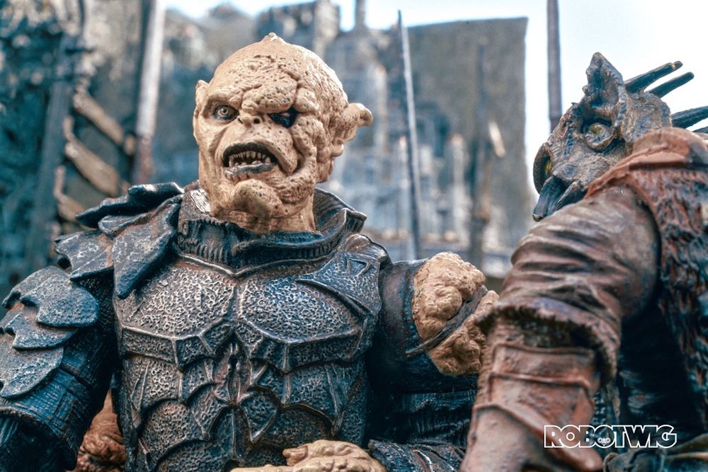 Gothmog stands in the middle of an army of orcs. Minus Tirith can be seen behind him.