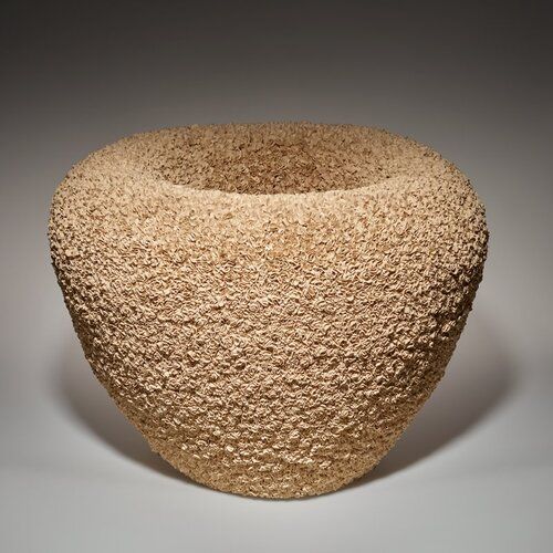 thick-walled vessel, flaring outward from base to wide shoulder, continuously curving inward toward inner walls; vessel covered overall, inner and outer walls, with small twisted and rolled elements with irregular edges, resembling flower petals; light beige color
Hattori Makiko’s process is meditative. She begins with a sculptural form to which she adds many thousands of tiny, shaved bits of clay to the whole surface in a long, relentless, repetitive process that she says requires a transcendent mindset.