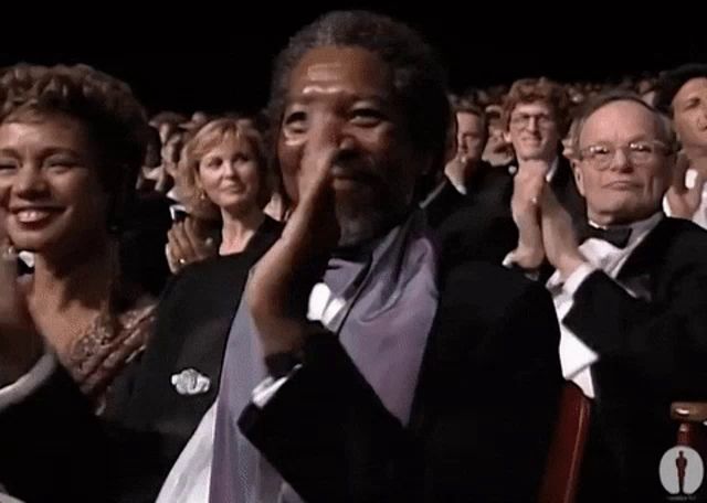 a man in a tuxedo is applauding in front of a crowd