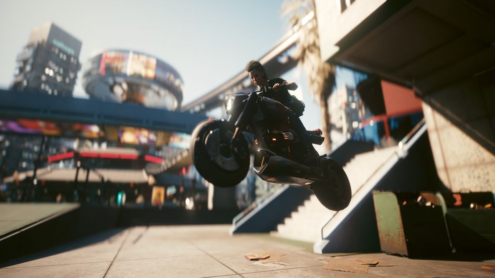 Cyberpunk 2077 screenshot: An action shot of V flying through the air on a sick motorcycle.