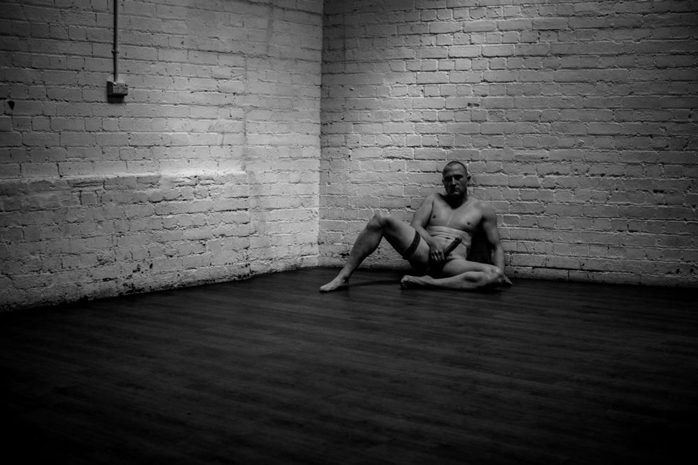 Male model reclined against white brick 