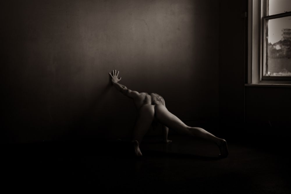 Male model facing the wall, left hand splayed on the wall 