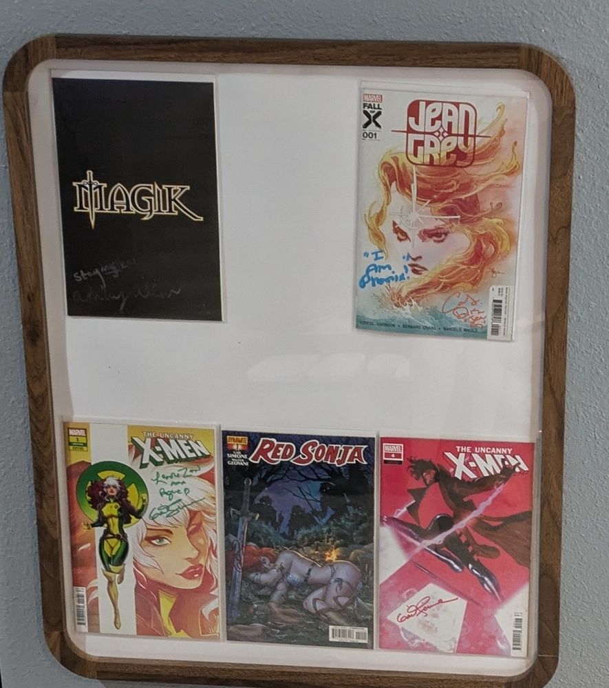A frame showing signed copies of Magic #1, Jean Gray #1, Uncanny X-Men #1, Red Sonja #1, and uncanny X-Men #4