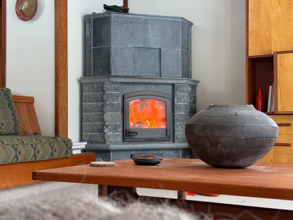 A gray fireplace in a MCM living room, with a table and vase in the foreground