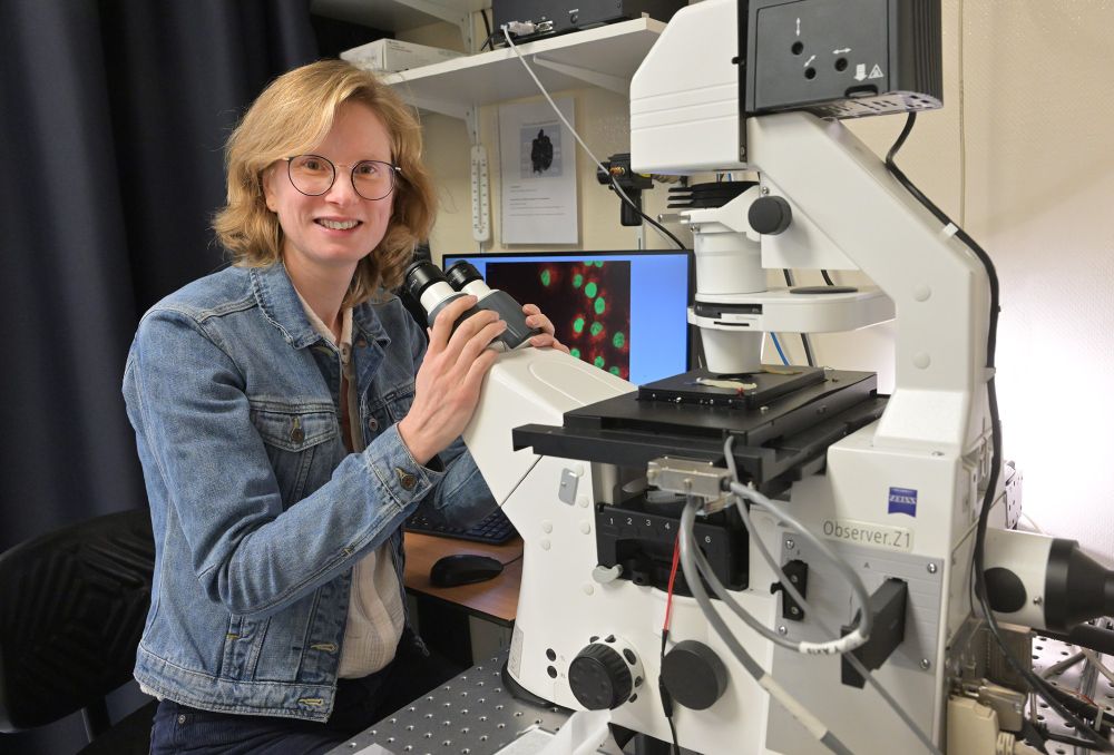 NKI Researcher Tineke Lenstra posing behind a microscope